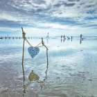 Heart tied up on wooden sticks at the beach Art Print