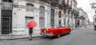 Woman with red umbrella by a vintage car on the street of Havana-Cuba Art Print