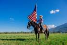 Man On Horseback Holds American Flag In Open Field Under Clear Blue Sky. Oregon, USA Art Print