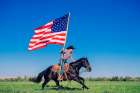 Cowboy On Horseback Waving Large American Flag In Open Green Field Under Clear Blue Sky. Oregon, USA Art Print