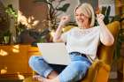 Cheerful Woman Sitting In Armchair At Home Celebrating Laptop Success Art Print