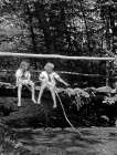1920S Pair Of Girls Sitting On Log Bridge Over Stream Holding Sticks Art Print