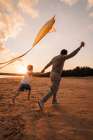 Father And Son Running With Kite On Beach At Golden Hour Art Print