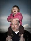Portrait Of A Young Girl At Dusk On Her Fathers Shoulders. Art Print