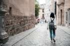 Woman With Backpack Walking On Cobblestone Street Alone Art Print