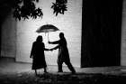 A Man Invites A Woman To Share His Umbrella As They Walk Outside In The Rain. Art Print