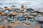 Waves Swirl Over Colorful Rounded Rocks On The Rocky Shore Of Pescadero State Beach, California. Art Print