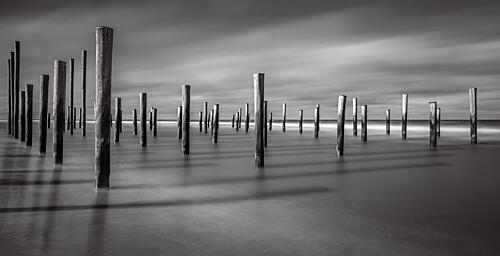 Calm Ocean Pilings Art Print by Hans van Zuijlen