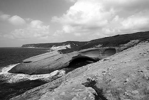 Flat rocks with natural arch on the coast of Sardinia Island ? black and white Coastal Print