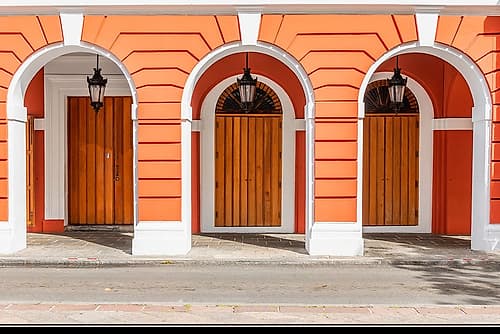 Orange Colonial Facade with Arched Wooden Doors Art Print